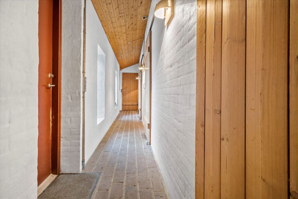 Rustikt arkitekttegnet hus fra 1980, teglstensgulv, vandskurede hvide vægge og trælofter